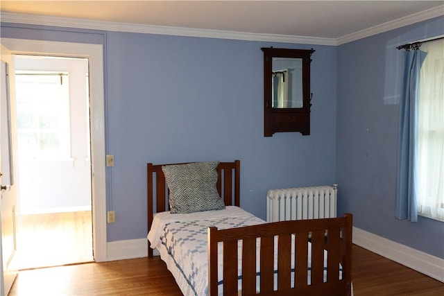 bedroom with radiator, dark hardwood / wood-style flooring, crown molding, and multiple windows