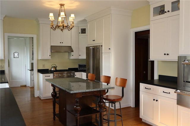 kitchen featuring a center island, decorative light fixtures, dark hardwood / wood-style flooring, a breakfast bar, and high end refrigerator