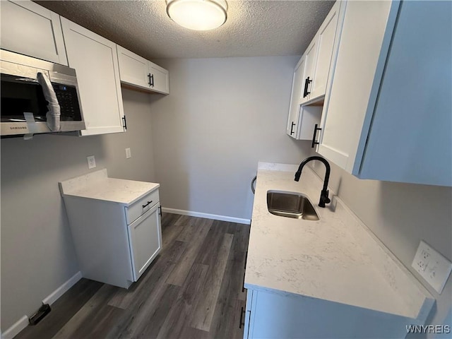 kitchen with dark hardwood / wood-style flooring, sink, white cabinetry, and a textured ceiling