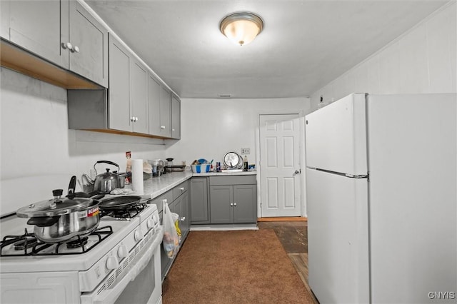 kitchen featuring dark carpet, white appliances, and gray cabinets