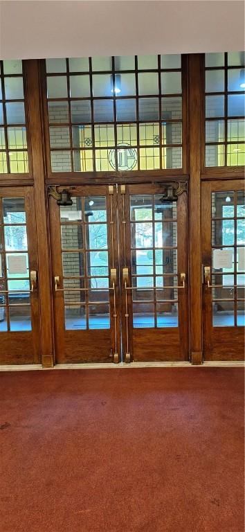 entryway with carpet, a towering ceiling, and french doors