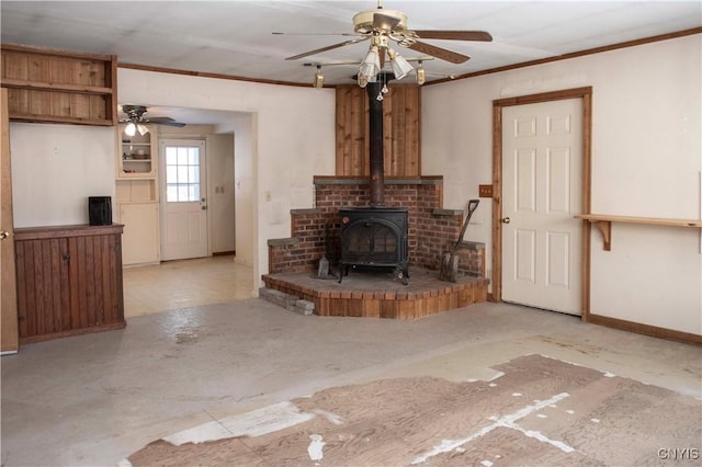 unfurnished living room featuring ceiling fan, a wood stove, and ornamental molding