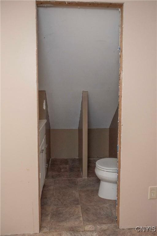 bathroom with toilet, vanity, and vaulted ceiling