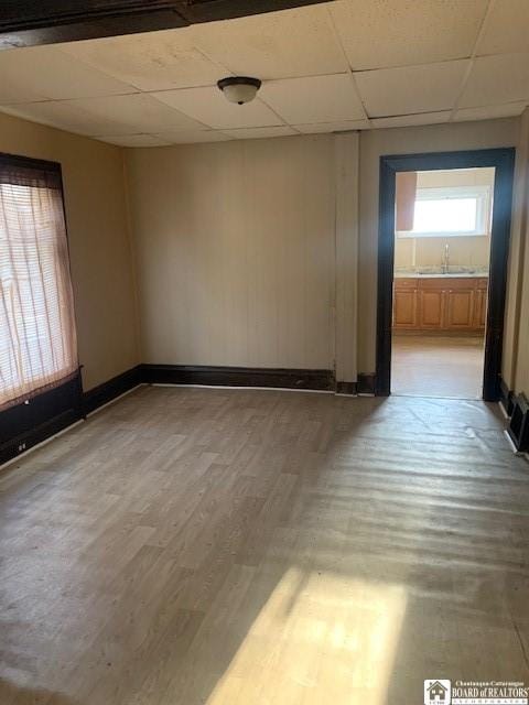 spare room with sink, wood-type flooring, and a paneled ceiling