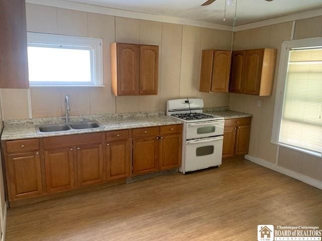 kitchen featuring double oven range, ceiling fan, light hardwood / wood-style floors, and sink