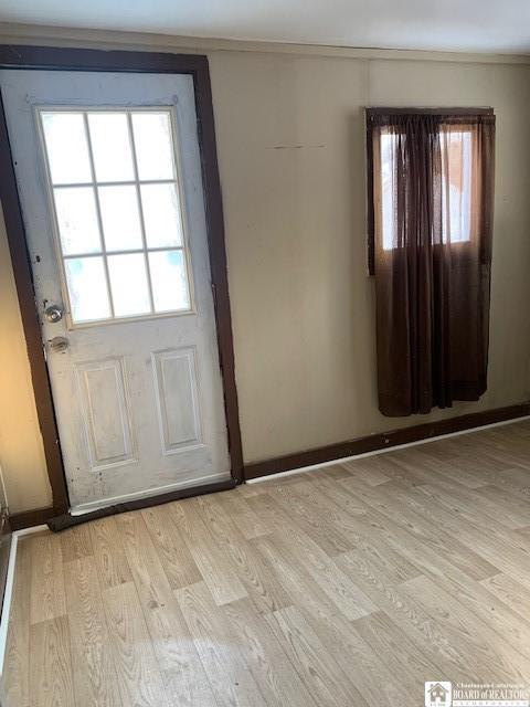 doorway with light hardwood / wood-style flooring and crown molding