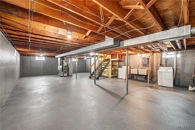 basement featuring heating unit, washer / clothes dryer, water heater, and sink