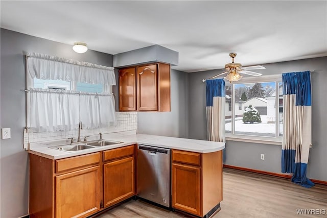 kitchen with kitchen peninsula, ceiling fan, backsplash, stainless steel dishwasher, and sink