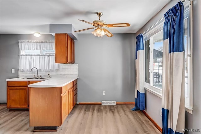 kitchen with tasteful backsplash, ceiling fan, sink, and light hardwood / wood-style flooring