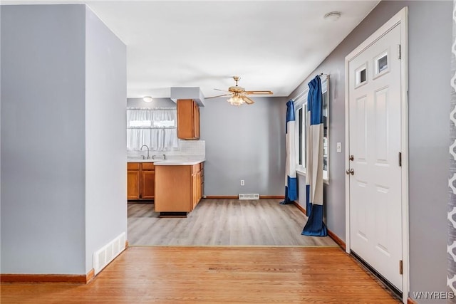 kitchen featuring ceiling fan, backsplash, light hardwood / wood-style flooring, and sink