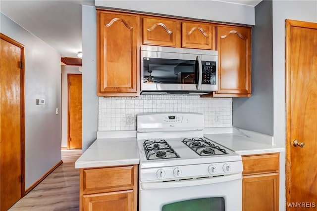 kitchen featuring light hardwood / wood-style flooring, white gas range, and tasteful backsplash