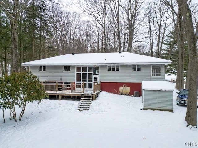 snow covered rear of property with a wooden deck