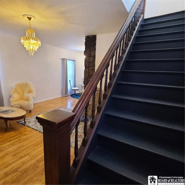 staircase with a chandelier and hardwood / wood-style flooring