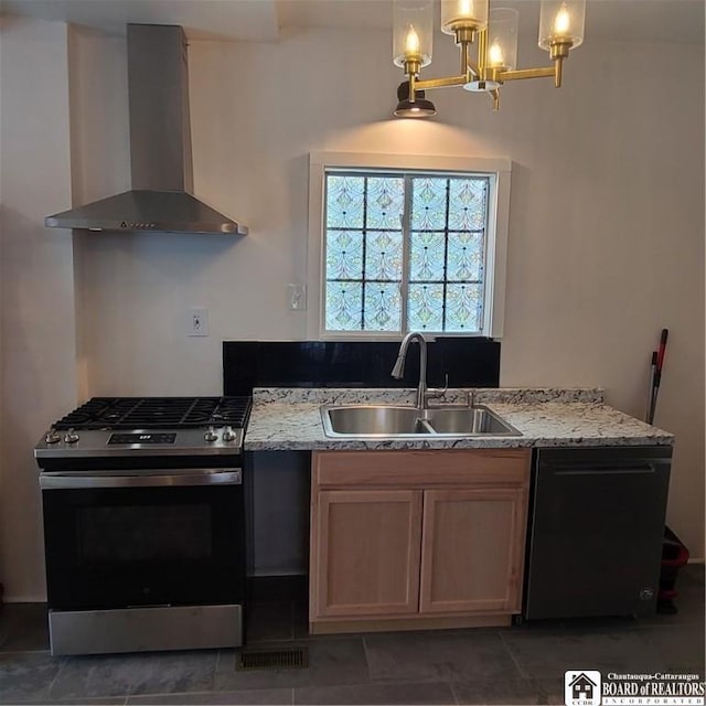 kitchen featuring stainless steel gas range, dishwasher, hanging light fixtures, wall chimney exhaust hood, and sink