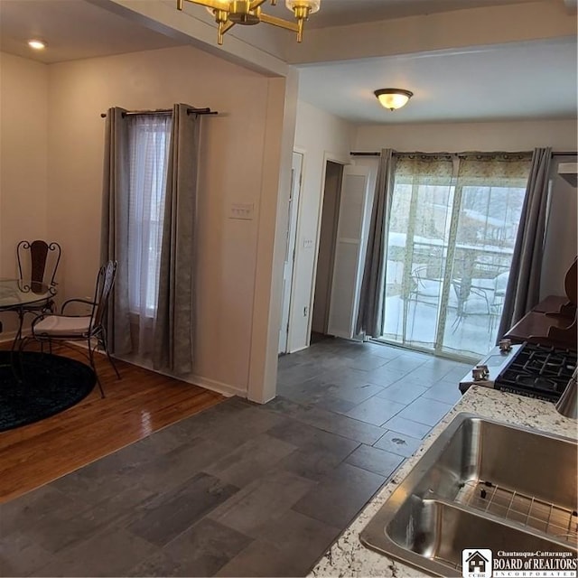 kitchen featuring dark hardwood / wood-style flooring, sink, an inviting chandelier, and stainless steel gas range