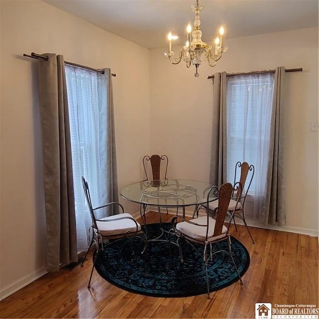 dining space with hardwood / wood-style floors and a notable chandelier