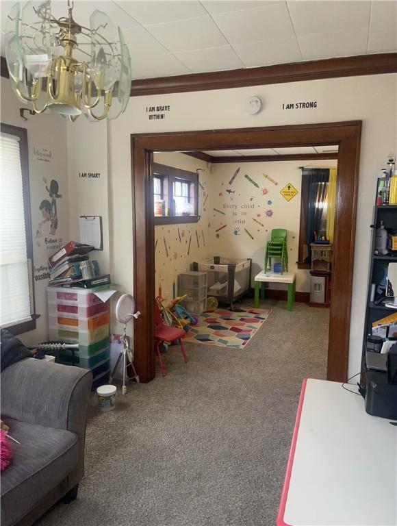 living room with carpet floors, crown molding, and a chandelier