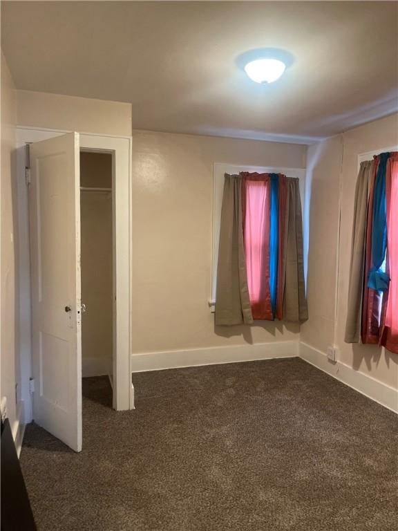 unfurnished bedroom featuring dark carpet and a closet