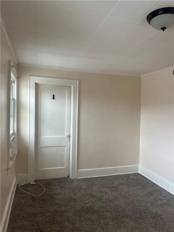 unfurnished room featuring ornamental molding and dark colored carpet