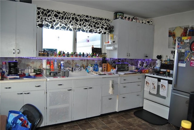 kitchen featuring white cabinetry, backsplash, stainless steel fridge, and white stove