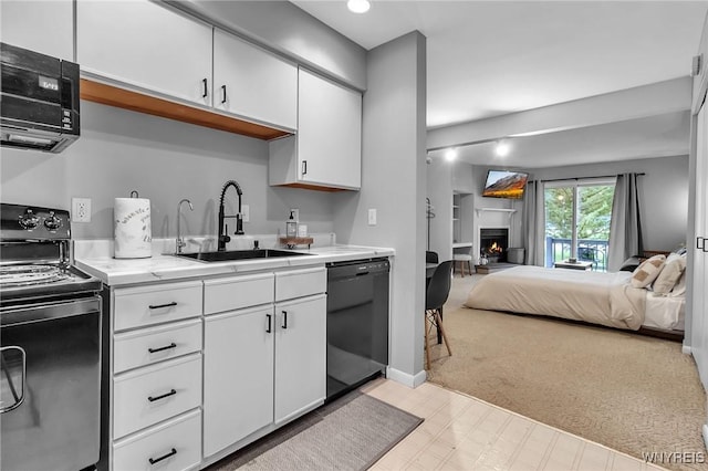 kitchen with sink, light colored carpet, white cabinets, and black appliances