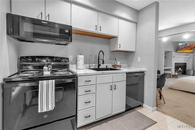 kitchen with light carpet, sink, white cabinets, and black appliances