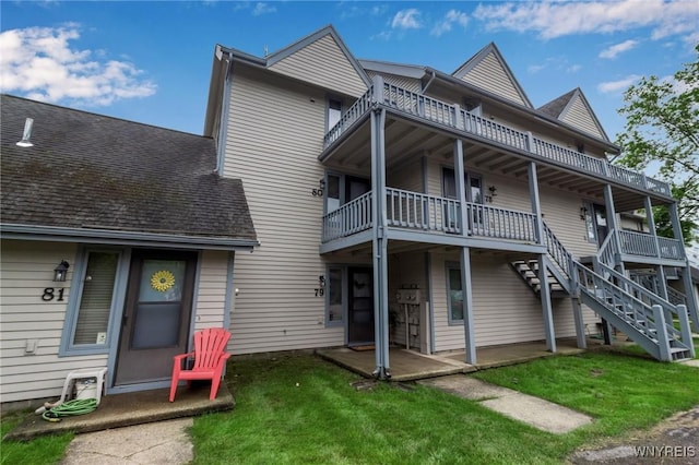 rear view of property with a balcony and a yard