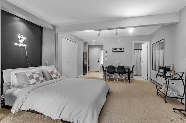 carpeted bedroom with black refrigerator, a closet, and track lighting