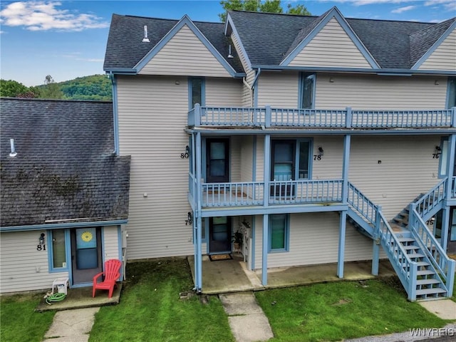 rear view of property with a yard, a patio area, and a balcony