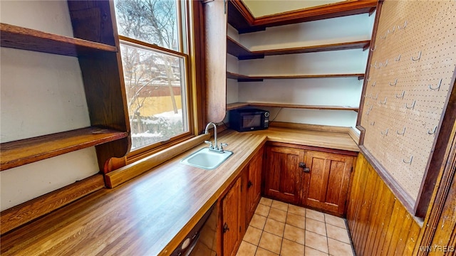 bar with a healthy amount of sunlight, sink, and light tile patterned flooring