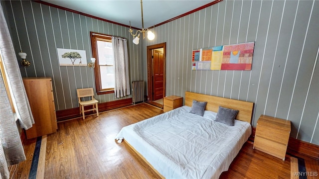 bedroom with ornamental molding, wood-type flooring, and radiator heating unit