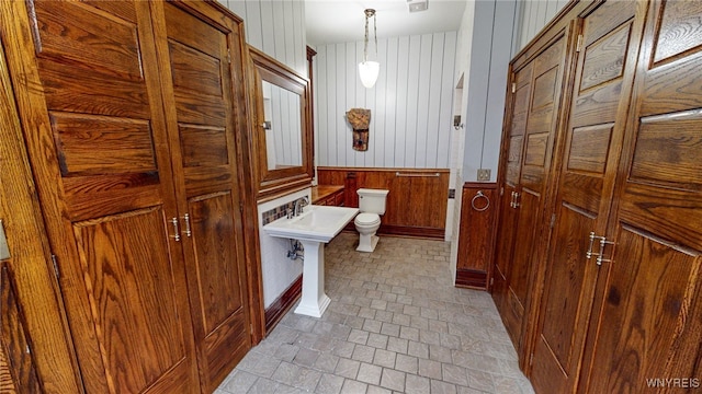 bathroom with toilet and wood walls