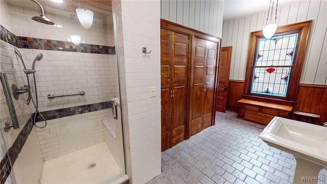 bathroom with a shower with shower door and wood walls