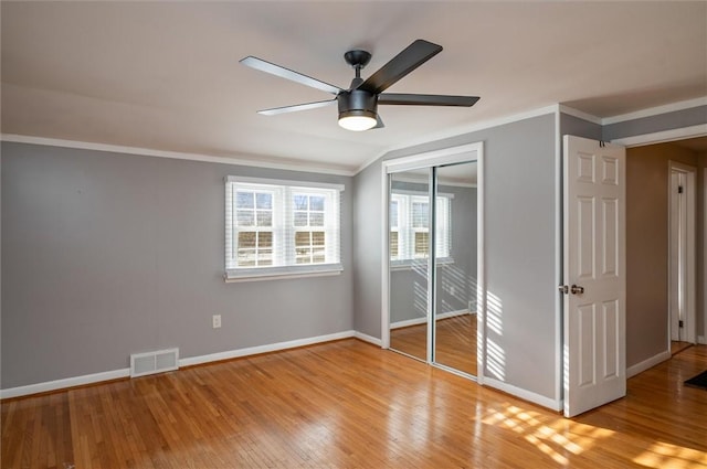 unfurnished bedroom with ceiling fan, a closet, light wood-type flooring, and crown molding