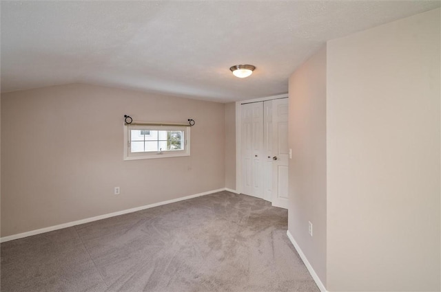 carpeted empty room with a textured ceiling and lofted ceiling