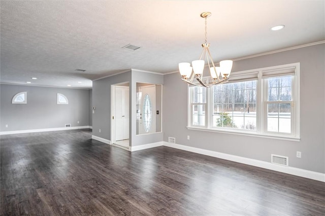 spare room featuring a textured ceiling, ornamental molding, dark hardwood / wood-style floors, and a notable chandelier