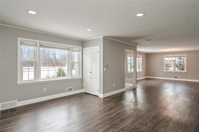 spare room with a textured ceiling, dark hardwood / wood-style flooring, crown molding, and a notable chandelier