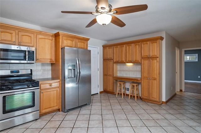 kitchen featuring ceiling fan, light tile patterned floors, backsplash, and appliances with stainless steel finishes