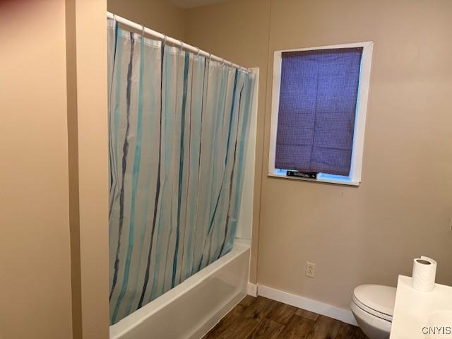 bathroom with toilet, shower / tub combo with curtain, and hardwood / wood-style flooring