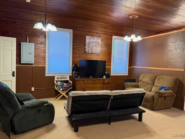 carpeted living room with a chandelier, wood ceiling, wooden walls, and electric panel