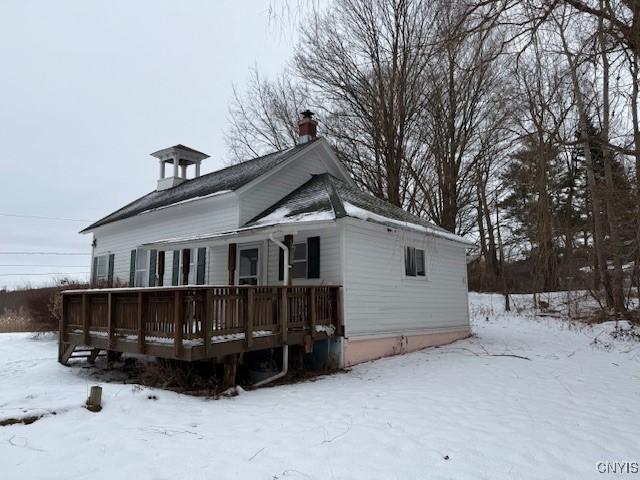 snow covered rear of property with a deck