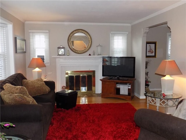 living room featuring a brick fireplace, crown molding, and wood-type flooring