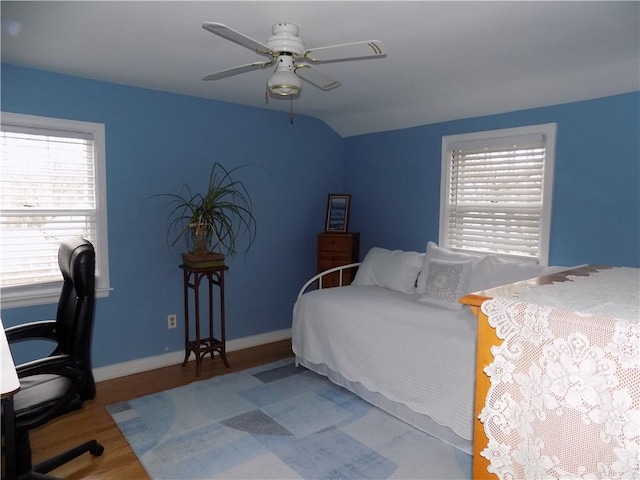 bedroom with ceiling fan, multiple windows, hardwood / wood-style flooring, and vaulted ceiling