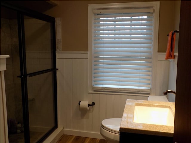 bathroom featuring hardwood / wood-style flooring, toilet, walk in shower, and vanity