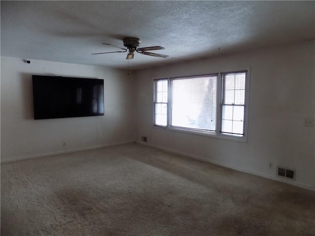 carpeted empty room featuring ceiling fan and a textured ceiling