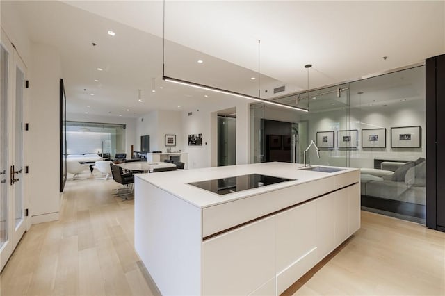 kitchen with pendant lighting, white cabinetry, sink, a large island, and black electric cooktop