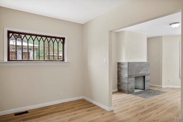 unfurnished living room with light wood-type flooring and a tile fireplace