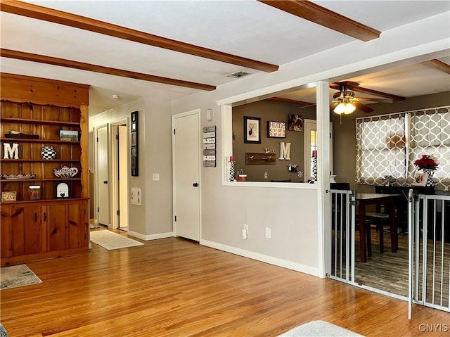 living room featuring ceiling fan, wood-type flooring, and beamed ceiling