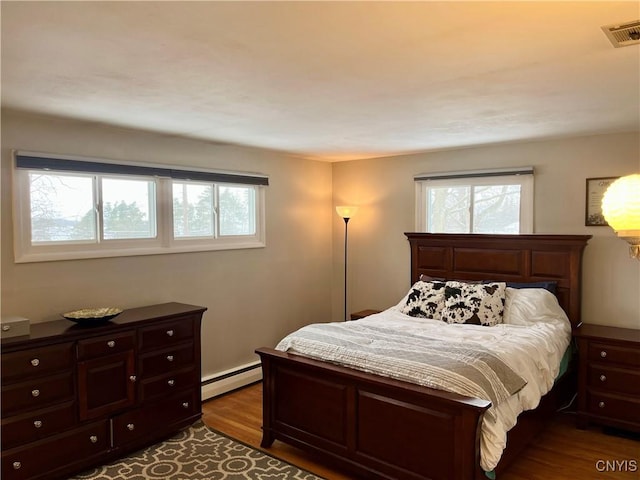 bedroom featuring baseboard heating and wood-type flooring