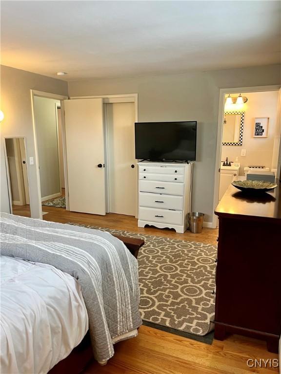 bedroom featuring hardwood / wood-style floors, ensuite bathroom, and a closet